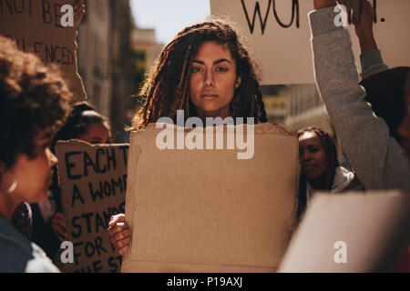 Schwere Frau mit einem leeren Plakat während eines Protestes im Freien. Gruppe der weiblichen Demonstranten auf der Straße bei Banner. Stockfoto