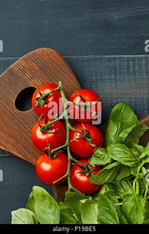 Frische organische Basilikum mit Kirschtomaten auf einem Holzbrett als gesundes Essen Stockfoto