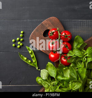 Zusammensetzung mit verschiedenen organischen Gemüse und hearbs auf schwarzem Holz- Hintergrund. Stockfoto