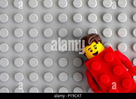 Tambow, Russische Föderation - Mai 20, 2018 LEGO Brick Red Suit Guy Minifigur auf grauen Grundplatte Hintergrund. Studio gedreht. Stockfoto