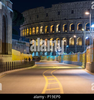 Rom, Italien, 25. März 2018: Die römischen Kolosseum steigt hinter die Bauarbeiten für die U-Bahn Linie C auf die Via dei Fori Imperiali in der Nacht. Stockfoto