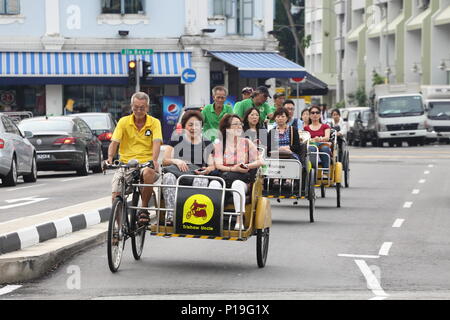 Eine Gruppe von glücklichen Touristen, die ihre Trischa-Fahrt genießen, um verschiedene Orte in der Stadt zu sehen. Singapur, Südostasien. Stockfoto