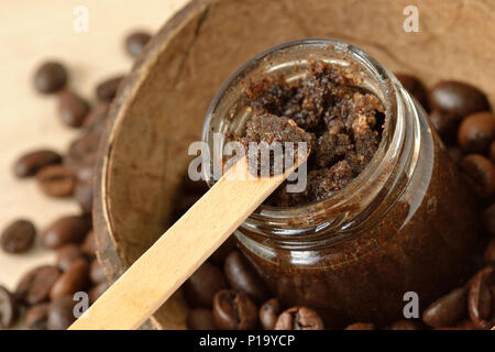 Hausgemachten Kaffee Peeling in einem Glas über Kokosnussschalen und Kaffeebohnen Stockfoto