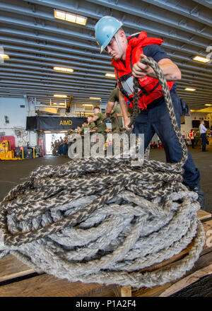151005-N-TH 560-1103 HONG KONG (Okt. 2010) 3, 2016) Seaman Cody Williams, von Woodbridge, Virginia, und Marines, 31 Marine Expeditionary Unit, hebe eine Linie im Hangar Bucht von Amphibisches Schiff USS BONHOMME RICHARD (LHD6) während einer Auffüllung auf See (RAS). Bonhomme Richard, dem Flaggschiff der Bonhomme Richard Expeditionary Strike Group, arbeitet im Südchinesischen Meer zur Unterstützung der Sicherheit und Stabilität in der Indo-Asia Pacific Region. (U.S. Marine Foto von Petty Officer 3. Klasse Jeanette Mullinax/Freigegeben) Stockfoto