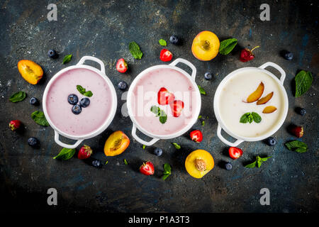 Verschiedene süße cremige Frucht & Berry Suppen, Erdbeere, Pfirsich, Blaubeere, Dunkelblau konkreten Hintergrund der Ansicht von oben kopieren Raum Stockfoto