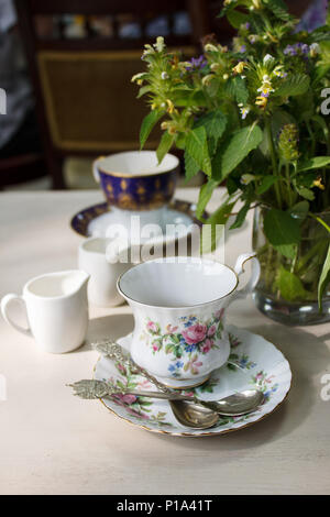 Vintage Porzellan Kaffeetasse, silber Kaffee Löffel und Blumenstrauß aus Sommer Wildblumen auf einen Tisch. Entspannenden gemütlichen alten Haus auf dem Land retro Atmosphäre. Stockfoto