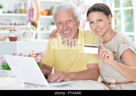 Älterer Mann mit junge Frau und Laptop mit Kreditkarte Stockfoto