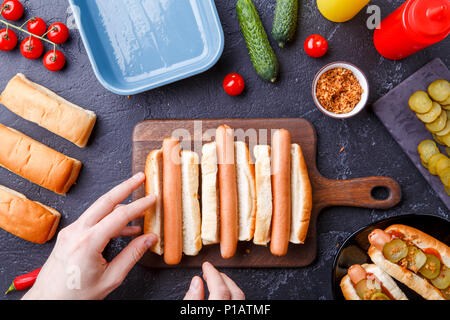 Bild von oben der Mann tun Hotdogs auf Schneidebrett auf Tabelle mit Würstchen Stockfoto