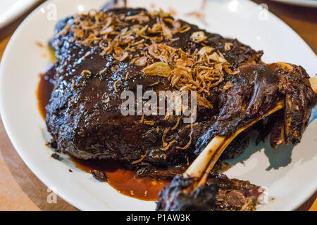 Geräucherter Lammschulter mit knusprigen Zwiebeln und Lamm Soße, auf weissem Platter. Stockfoto