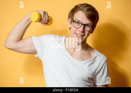 Freundliche Schüler Übungen mit gelben Hantelset von auf dem gelben Hintergrund Stockfoto