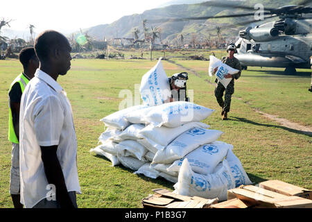 Hatian Staatsangehörigen zusehen, wie Marines mit dem 24 Marine Expeditionary Unit 50kg-Säcke Reis an einem abgelegenen Dorf in der Republik Haiti Okt. 2016 entladen. Elf Marines links USS Mesa Verde (LPD 19) und nach Haiti International Airport, wo Sie auf 7.500 lbs der humanitären Hilfsgüter reiste, nahm dann die Beihilfe von einem CH-53E Super Stallion geliefert. Diese und andere Vermögenswerte mit dem 24 MEU bieten Schwergut- Funktionen zur Task Force Matthäus und US Southern Command, die mit einer abgestimmten erste militärische Unterstützung für die Regierung von Haiti Anfrage für eine Antwort Stockfoto