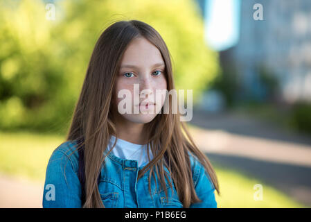 Junges Mädchen mit schönen langen Haaren. Sommersprossen im Gesicht. Stellt die Kamera starrt. Im Sommer im Park an der frischen Luft. Nachdenklich träumt er in seinem Kopf. Stockfoto