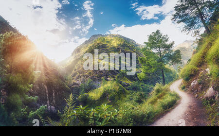 Erstaunliche Szene mit Himalaya grünes Gras und Bäumen bedeckt, blau bewölkten Himmel mit Sonne, Wolken und schönen Weg in Nepal bei Sonnenuntergang. Panorami Stockfoto