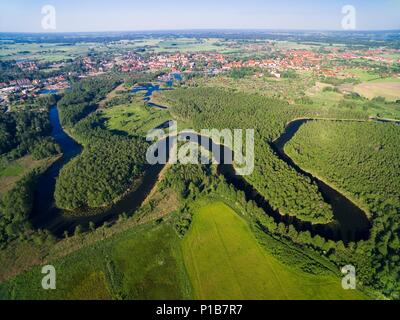 Mäander der Wegorapa Fluss über Feuchtgebiete, Mazury, Polen. Wegorzewo Stadt im Hintergrund Stockfoto