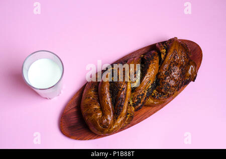 Brötchen mit Mohn und ein Glas Milch auf einem rosa Hintergrund Stockfoto