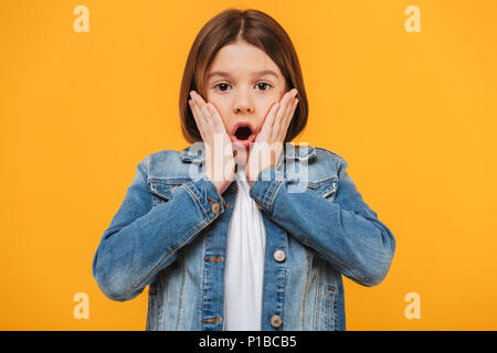 Porträt einer überrascht kleines Schulmädchen an Kamera auf gelbem Hintergrund Stockfoto