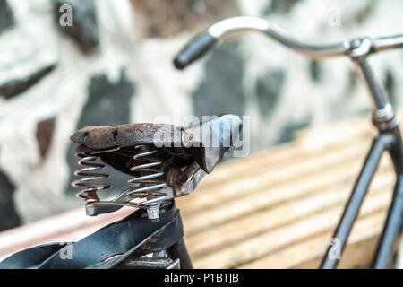 Ein altes Fahrrad mit einer Feder Stoßdämpfer. Vintage Fahrrad auf der Steinmauer Hintergrund. Stockfoto