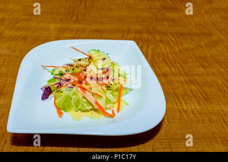 Appetitliche Salat von frischem Gemüse auf einem weißen Porzellanteller auf braunem Holz- Tabelle Stockfoto