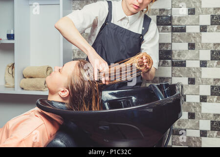 Haare waschen Verfahren in einem Schönheitssalon. Ein Friseur ist das Waschen ihrer Kunden in professionelle Waschbecken Stockfoto