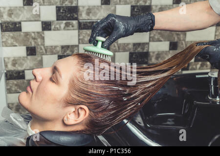 Haarpflege Verfahren im Beauty Salon. Friseur ist das Putzen der Frau Haar Verbreitung einer Behandlung Maske oder Conditioner Stockfoto