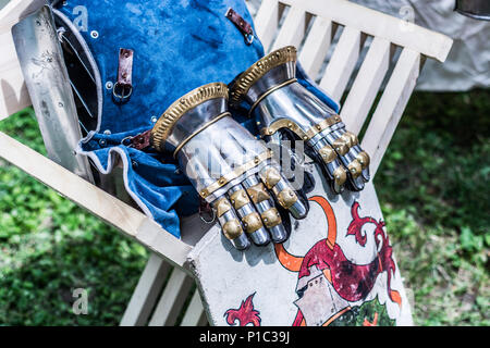 Mittelalterliche Ritter metall hand Handschuhe und Schild auf hölzernen Stuhl. Traditionelle Ritter Waffen, die im mittleren Alter Thema Festival Stockfoto