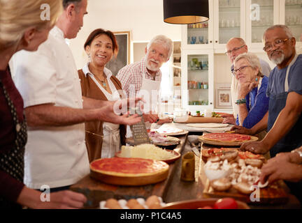 Ältere Freunde hören Chef in Pizza Kochkurs Stockfoto