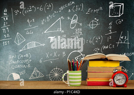 Das zusammengesetzte Bild im Stapel der Bücher von Becher mit Buntstiften und Wecker auf hölzernen Tisch Stockfoto