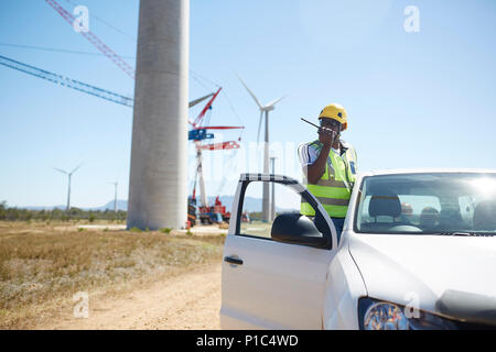 Ingenieur mit walkie-talkie bei Fahrzeug bei Sunny Windenergieanlage Kraftwerk Stockfoto