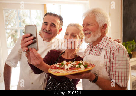 Koch und Senior Paar unter selfie mit Pizza im Kochkurs Stockfoto