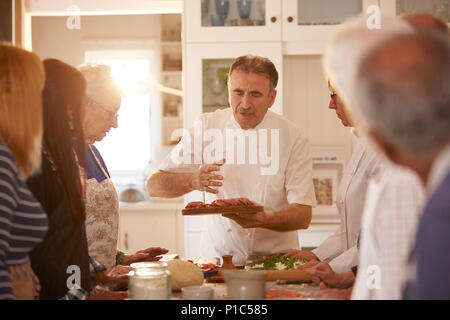 Ältere Freunde hören Chef in Pizza Kochkurs Stockfoto