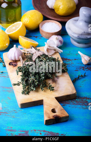 Bündel von frischem Thymian, Zitrone und Knoblauch auf Holz Schneidebrett. Zutaten der traditionellen mediterranen Küche Stockfoto