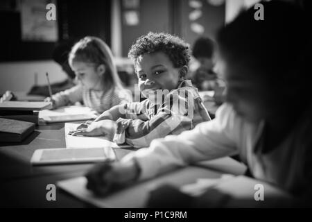 Portrait von lächelnden Schuljungen seine Hausaufgaben im Unterricht Stockfoto