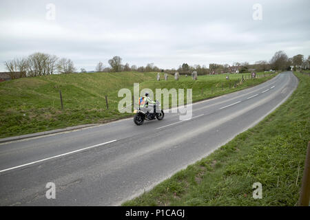 Motorrad fahren Ein 4361 Straße durch Henge aus kreisförmigen Bank und Graben um Steinkreis von Avebury avebury Wiltshire England Großbritannien Stockfoto