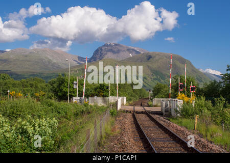 Blick auf den Bahnübergang an Bavanie Station in der Nähe von Fort William, Schottland, mit Ben Nevis, den höchsten Berg in Großbritannien, sichtbar hinter sich. Stockfoto