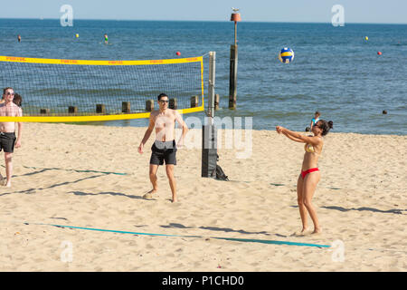 Junge Leute, beim Beach Volleyball an der Südküste von England in Boscombe, Bournemouth, Dorset, Großbritannien während einer Hitzewelle in einer außergewöhnlich sonnigen Bann der Sommer Wetter. Stockfoto