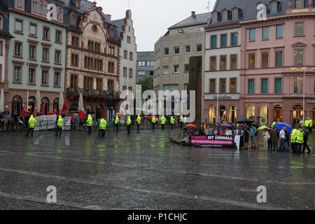 Mainz, Deutschland. 11. Juni 2018. Eine Handvoll Rechtsradikalen demonstrant sich mitten auf dem Platz vor der Kathedrale im Regen. Rund 300 Menschen folgten dem Aufruf der lokalen Gewerkschaften und Kirchen zu einer Mahnwache in der Innenstadt von Mainz, die getöteten Teenager Suanna F., trotz des schweren Regens erinnern. Sie sind die Kerzen im Gedenken an die Opfer. Die rechten 'Kandel ist uberall" (Kandel ist überall) Bewegung hielt eine Rallye unter dem Vorwand der Tötung zur gleichen Zeit in der Nähe. Quelle: Michael Debets/Alamy leben Nachrichten Stockfoto