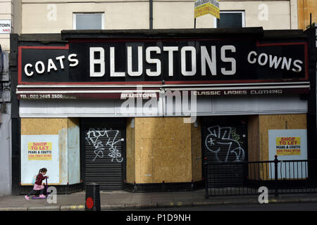 Menschen gehen vorbei ist ein Geentert und geschlossen Frauen Mode Shop auf Kentish Town Road. Die Geschäfte sind geschlossen und die High Street ist in der Abnahme als Menschen Stockfoto