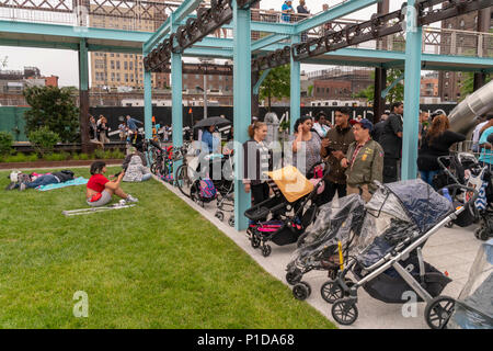 Trotz des rauhen Wetters tausende Besucher strömten zu Eröffnung von Domino Park in der Nachbarschaft von Brooklyn Williamsburg in New York am Sonntag, den 10. Juni 2018. Die Website der Domino Sugar Co. Raffinerie zu besetzen, wurde 2004 geschlossen, die fünf Hektar großen greenspace hat Wasser, Rutschen, einen erhöhten Laufsteg, Danny Meyer Essen stehen und Volleyball sowie viele andere Annehmlichkeiten. Von James Corner Field Operations konzipiert, die Architekten hinter dem Design der High Line, der Backstein Raffinerie Gebäude, die gleichzeitig 50 Prozent aller Zucker in den USA verarbeitet bleibt für de Stockfoto