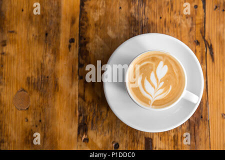 Tasse Kaffee zu gehen auf dem Holztisch mit Latte Art Street Kaffee. Ansicht von oben Stockfoto