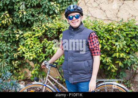 Eine junge lächelnde Mann bycyclein den Garten. Stockfoto