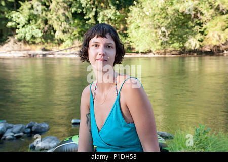 Das Porträt einer Frau sitzt an einem Fluss. Stockfoto