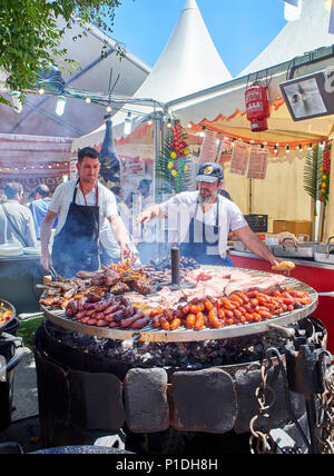 Madrid, Spanien - 15. Mai 2018. Hispanic Köche kochen Würstchen Schweinefleisch Spare Ribs und andere Fleisch auf einem Holzkohle Grill in einem Stall eines Street Food Fair. Stockfoto