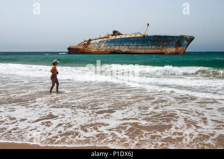 Frau am Strand mit Wrack der American Star im Hintergrund an der Westküste von Fuerteventura, Kanarische Inseln, Spanien Stockfoto