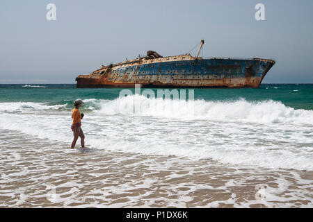 Frau am Strand mit Wrack der American Star im Hintergrund an der Westküste von Fuerteventura, Kanarische Inseln, Spanien Stockfoto