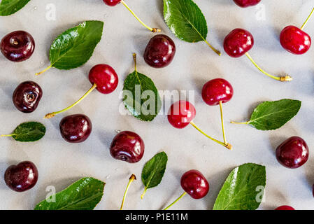 Süße reife Kirschen und Blätter auf weißem Hintergrund Stockfoto