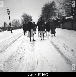 1950, historische, eine Gruppe junger Damen zusammen auf einer verschneiten Straße auf dem Weg nach Hause nach der Fertigung der Hochschule, England, UK. Stockfoto