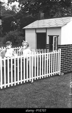 1947, Sommer und zwei junge Kinder, ein Junge und ein Mädchen haben Kaffee zusammen sitzen in einem geschlossenen Raum außerhalb ihrer Spielhaus im Garten, England, UK. Stockfoto