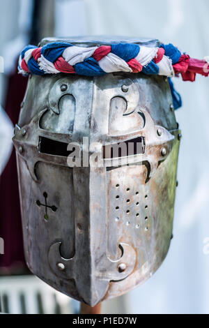 Bügeleisen Helm der mittelalterlichen Ritter auf Holz Stativ mit roten, blauen und weißen Band. Mittelalter Rüstung Konzept. Close Up, selektiver Fokus Stockfoto