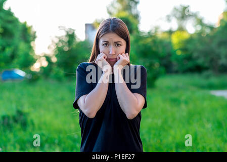 Schöne brünette Mädchen. Im Sommer im Park auf Urlaub. Emotionale Mimik, fürchte ich. Angst Frau. Stockfoto