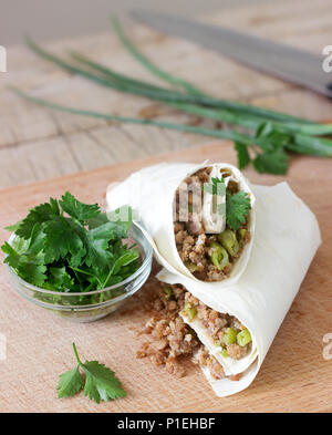 Burrito oder shawurma mit Hackfleisch und grüne Bohnen auf einem Holzbrett. Selektive konzentrieren. Stockfoto